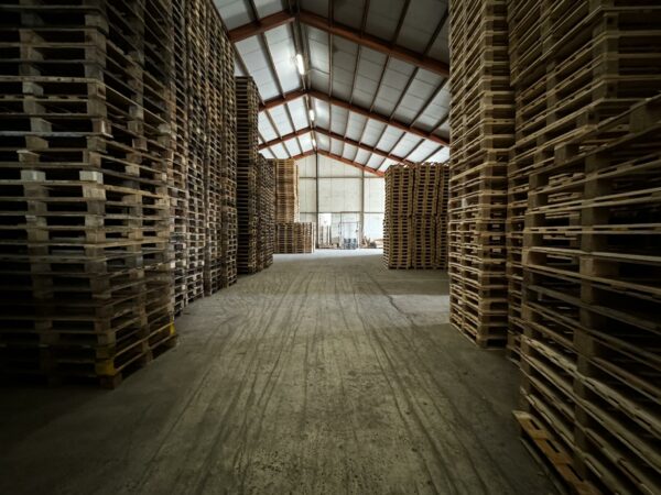 Hoge stapels houten pallets in een ruime loods aan de Graaf van Lynden van Sandenburgweg.
